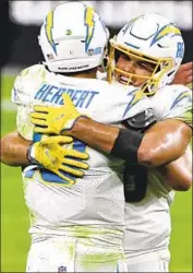  ?? David Becker Associated Press ?? HUNTER HENRY, right, embracing quarterbac­k Justin Herbert, is not expected to be available Sunday.