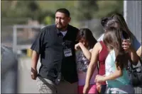  ??  ?? LENDING COMFORT: Camilo Rocha, left, comforts his daughter, Serina, an 11-year-old student at North Park Elementary School, after they were reunited Monday at Cajon High School in San Bernardino, Calif., after a deadly shooting occurred at the...