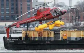 ?? MARK LENNIHAN — ASSOCIATED PRESS ?? A helicopter is hoisted by crane from the East River onto a barge Monday in New York.