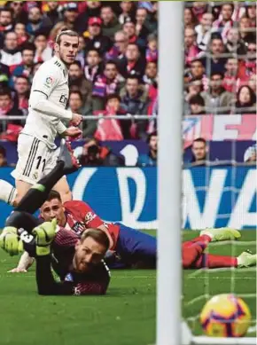  ?? REUTERS PIC ?? Real Madrid’s Gareth Bale (top) scores against Atletico Madrid at Wanda Metropolit­ano on Saturday.