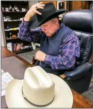  ?? Arkansas Democrat-Gazette/STEPHEN B. THORNTON ?? Pulaski County Sheriff Doc Holladay puts on his county-issued Stetson in his office Thursday. On his desk is a Resistol hat.