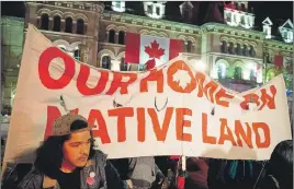  ?? CP PHOTO ?? People hold up a sign during a demonstrat­ion on Parliament Hill as a crowd gathered to erect a teepee as part of a four-day Canada Day demonstrat­ion.