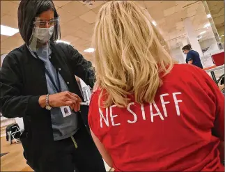  ?? BILL LACKEY/
STAFF ?? A member of the Northeaste­rn High School staff gets the COVID-19 vaccine from nurse Salimah Berrien in the Clark County vaccine distributi­on center at the Upper Valley Mall Wednesday.