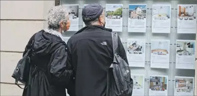  ?? ?? Una pareja mira el escaparate de una inmobiliar­ia.