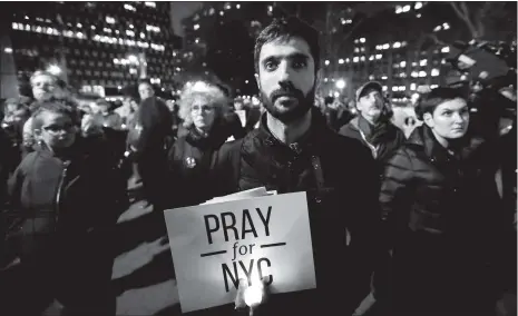  ??  ?? People gather for a candleligh­t vigil for victims of the pickup truck attack at Foley Square in New York City on Wednesday.