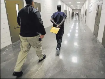  ?? John Gibbins San Diego Union-Tribune ?? An asylum seeker in 2017 is moved by a guard at the ICE Imperial Regional Detention Facility in Calexico, Calif.