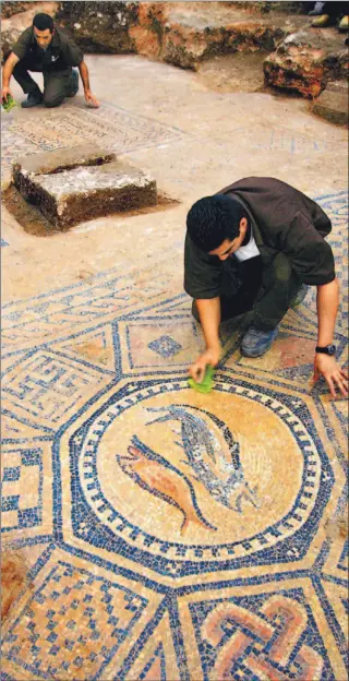 ?? DAVID SILVERMAN/ GETTY IMAGES ?? Prisoners clean dirt from an early Christian mosaic in the ruins of an ancient church that was recently excavated in the grounds of a prison in Megiddo (also known as Armageddon) in northern Israel.