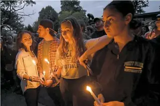  ?? Matt Freed/Post-Gazette ?? Katie Maurer, 19, of Hilton Head, S.C.; Eric Riederer, 21, of Buffalo, N.Y.; Marina Karis, 19, of Hilton Head; and Jaden Murphy, 19, of West Palm Beach, Fla., hold candles during a vigil for rapper Mac Miller on Sept. 11 at Blue Slide Park in Squirrel Hill.