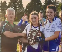  ?? ?? U14 football joint captains Grace Roche and Cara Burke, being presented with the North Cork D2 Football Shield by referee Dick O’Sullivan.