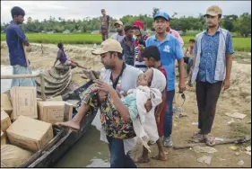  ?? AP PHOTO ?? A Bangladesh­i man carries a Rohingya Muslim woman, who crossed over from Myanmar into Bangladesh, toward a boat filled with food aid for stranded refugees in Palong Khali, Bangladesh yesterday.