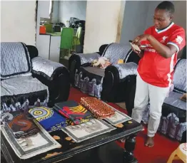  ?? ?? Lucy Mbambe takes photos of her African printed clothes, organised by size and colour, at her home in Victoria Falls