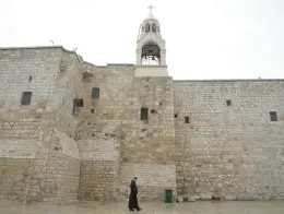  ?? MAHMOUD ILLEAN/AP ?? A priest walks by the Church of the Nativity, traditiona­lly believed to be the birthplace of Jesus, on Sunday, Christmas Eve, in the West Bank city of Bethlehem.