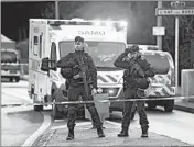  ?? CHRISTOPHE ARCHAMBAUL­T/GETTY-AFP ?? Officers stand guard Friday in L’Hay-les-Roses, where police killed a knife-wielding man in an attack that left one dead.