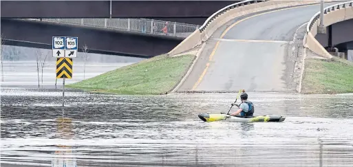  ?? ANDREW VAUGHAN/THE CANADIAN PRESS ?? A kayaker makes his way past a flooded highway ramp on Saturday. Water levels are rising rapidly on the St. John River, pushing it past the flood stage.