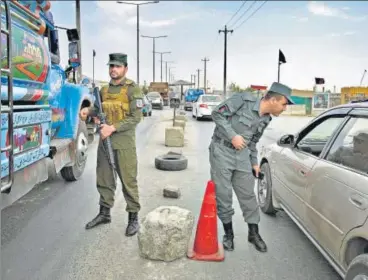  ??  ?? Afghan policemen stand guard at a checkpoint along the road in Kabul on Saturday