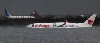  ?? REUTERS ?? The body of a Lion Air Boeing 737 plane is seen in the water after it missed the runway in Denpasar, Bali, on Saturday. All 108 passengers and crew survived when the jet landed in shallow water, government officials said.
