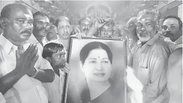  ?? — AFP photo ?? Supporters hold a photograph of Jayalalith­aa as they offer prayers for her well being at a temple in Mumbai.