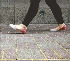  ?? AFP ?? A woman walks over a glue-reinforced pavement to prevent protesters from using the bricks as projectile­s during protests.