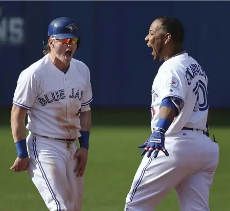  ?? RICHARD LAUTENS/TORONTO STAR ?? Josh Donladson, left, joins Edwin Encarnacio­n in celebratin­g his game-winning single in the ninth, also Encarnacio­n’s 125th RBI of the season.