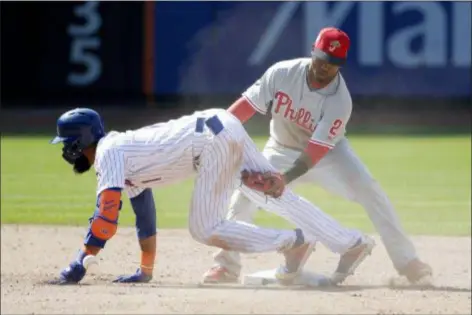  ?? SETH WENIG — THE ASSOCIATED PRESS ?? Phillies’ shortstop Jean Segura, right, loses the ball before tagging the Mets’ Amed Rosario during the ninth inning Sunday. The Phillies won, 8-3.