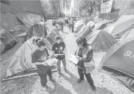  ?? ARLEN REDEKOP, VANCOUVER SUN ?? Camp residents read a notice they received from the city telling them they have to leave.