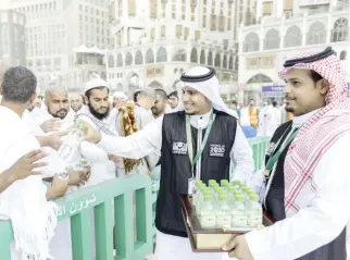  ??  ?? Young Saudi volunteers distribute water bottles to pilgrims in Makkah. (SPA)