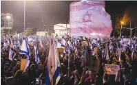  ?? (Amir Levy/Getty Images) ?? PROTESTERS HOLD flags during a rally against the government, on Saturday night in Tel Aviv.