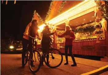  ??  ?? Visitors with bicycles place their orders at the drive in the Christmas market in Landshut, southern Germany.