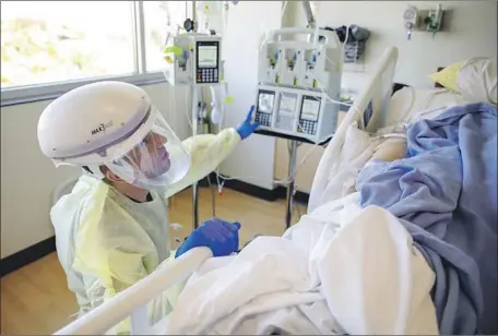  ?? Kaden D. Pitt DVIDS U.S. Army ?? ARMY 1st Lt. Blaine Woodcock, a critical care nurse, helps a COVID patient at Kootenai Health medical center in Coeur d’Alene, Idaho.