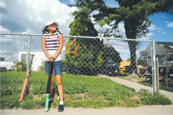  ??  ?? MaKayla Cortez waits to bat during a game with her siblings. Phyllis Cortez’s grandchild­ren Lily, Santiago and MaKayla spend much of their hot summer days playing oldfashion­ed pick-up baseball in the street outside of the home she shares with her wife,...