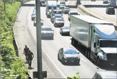  ??  ?? Traffic crawls by as Stamford police officers continue to search the embankment adjacent to I-95 northbound around the area of the Fairfield Avenue overpass following a reported shooting on Tuesday.