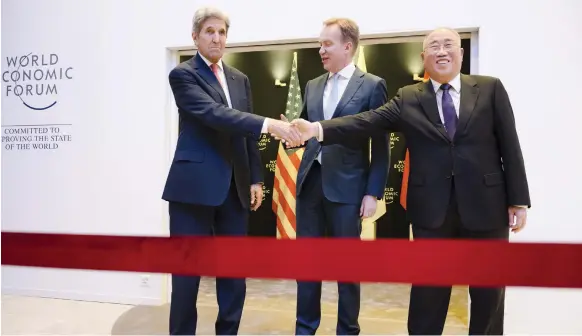  ?? EPA ?? John Kerry, the US climate envoy, shakes hands yesterday with Xie Zhenhua, China’s special envoy for climate, next to Borge Brende, President of the World Economic Forum, in Davos, Switzerlan­d. Mr Kerry has said it is possible to meet European energy shortages without going back on efforts to tackle climate change