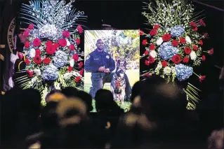  ?? JOSEPH FORZANO / THE PALM BEACH POST ?? A photo of Boynton Beach Police officer Joseph Crowder and his canine partner, Daxxx, is displayed at the memorial Thursday for Crowder at Christ Fellowship Church in Boynton Beach. Crowder died suddenly while jogging Dec. 12.