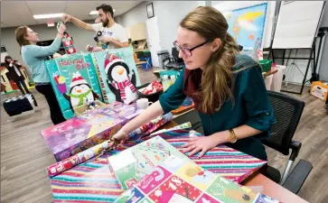  ?? @IMartensHe­rald Herald photo by Ian Martens ?? Katelyn de Boer and members of the Urban Spirits Rotary Club wrap presents Monday evening after a donation from Ron and Joyce Sakamoto came in to help with the shortfall for Lethbridge Family Services’ Angel Tree Christmas Campaign.