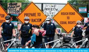  ?? — AFP ?? WASHINGTON: Washington Police officers watch demonstrat­ors as they march on the street at the fence in Lafayette Park, near the White House.