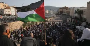  ?? Associated Press ?? ■ A Palestinia­n flag flies over the annual Land Day rally on March 30 in the Arab city of Arraba, northern Israel. Land Day rallies by Palestinia­ns protest what they say are discrimina­tory policies and to commemorat­e the deaths of six Arab protesters who were killed by police on March 30, 1976, while demonstrat­ing against an Israeli plan to confiscate Arab land.