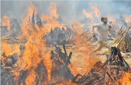  ?? Photo / AP ?? A man runs to escape heat from the funeral pyres at a crematoriu­m in the outskirts of New Delhi.