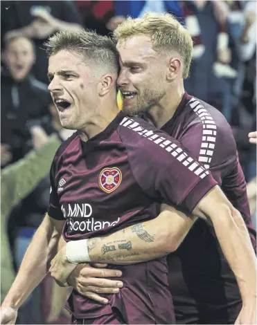  ?? ?? Nathaniel Atkinson gives two-goal hero Cammy Devlin a hug at Tynecastle last night