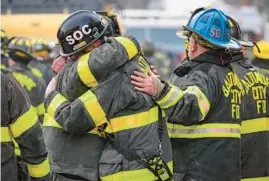  ?? JERRY JACKSON/BALTIMORE SUN ?? Baltimore City firefighte­rs embrace after the body of Lt. Paul Butrim was taken from the scene of a vacant rowhouse fire on South Stricker Street in January. Three firefighte­rs died in the blaze.