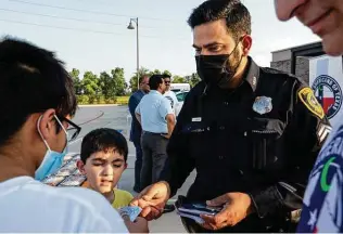  ?? Godofredo A. Vásquez / Staff photograph­er ?? Houston Police Department senior officer Danish Hussain gives away stickers to two boys who were distributi­ng food to fellow Muslims for iftar on Monday in Sugar Land.