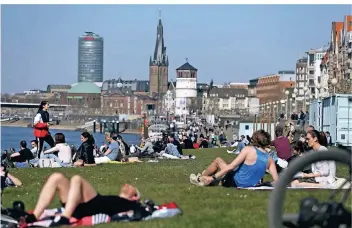  ?? FOTO: DAVID YOUNG/DPA ?? Auf den Wiesen an der Rheinuferp­romenade in der Düsseldorf­er Altstadt war es am Sonntag voll – die Menschen hielten aber zumeist Abstand.