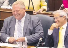  ??  ?? Premier Doug Ford, left, shares a laugh with Finance Minister Vic Fedeli at the Ontario legislatur­e on Monday. Ford wants to streamline decision-making on Toronto city council and save city taxpayers $25 million in salaries by reducing councillor­s.