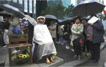  ??  ?? South Korean protesters stand next to a statue of a teenage girl symbolisin­g former ‘comfort women’, who served as sex slaves for Japanese soldiers during World War II, during a weekly anti-Japanese demonstrat­ion near the Japanese embassy in Seoul. — AFP photo