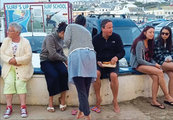  ??  ?? Anonymous: David Cameron sits on a beach wall to eat fish and chips during a recent holiday in Cornwall as those around him seem oblivious to the fact he is the former PM