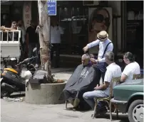  ?? AFP ?? ‘Abo Tawila’ gives a client a haircut on a street in the Lebanese capital Beirut’s southern suburbs. —