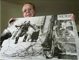  ??  ?? Fotograf Peter Leibing med sitt verdenskje­nte fotografi av Conrad Schumann som hopper over piggtrådsp­erringene som skilte Øst- og Vest-Berlin.