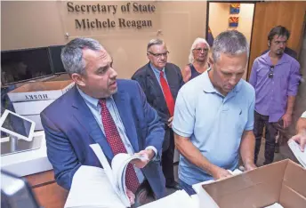  ??  ?? Eric Spencer, left, director of election services for the Secretary of State’s Office, looks over petitions filed by former Maricopa County Sheriff Joe Arpaio (standing behind) on Tuesday at the State Capitol. Arpaio is running in the Republican...