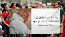  ?? PHOTO: REUTERS ?? People hold a banner with a picture of Father Jacques Hamel, which reads ‘‘Where there is hatred, let me sow love’’, after a mass paying tribute to the murdered priest at Notre-dame Cathedral in Paris.