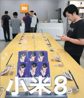  ?? REUTERS ?? A customer checks out a smartphone at a Xiaomi store in Beijing.