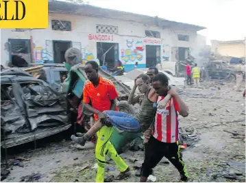  ?? FARAH ABDI WARSAMEH / THE ASSOCIATED PRESS ?? Somalis carry away a man injured by a car bomb at a hotel in Mogadishu, Somalia on Saturday. The attack, which killed 23, as well as one two weeks ago that killed 350 on a city street, has shaken public confidence in the military.